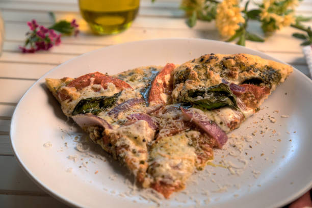 Side view and closeup of vegetarian pesto pizza on white plate. stock photo