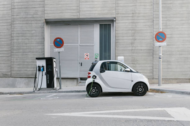 Side view of a white electric car in a charging station while getting charged stock photo
