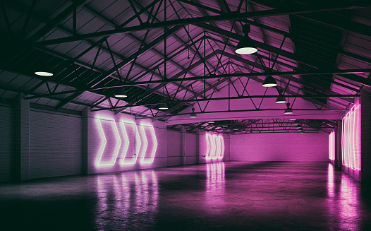 Side view of an empty large and long warehouse interior with cement floor, illuminated by lots of pink arrow shaped neon lights from side brick walls. A large blank brick wall background with copy space at the end. Slight vintage effect applied. 3D rendered image.