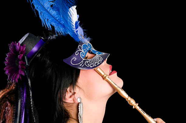 Side view of black haired beauty in blue mask. Horizontal studio shot on black of woman in mini top hat and blue mardi-gras style mask. mardi gras women stock pictures, royalty-free photos & images