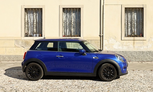 Udine, Italy. March 5, 2022. Blue Mini One, also called Mini cooper or Min Hatch, on a cobblestone road in the town.