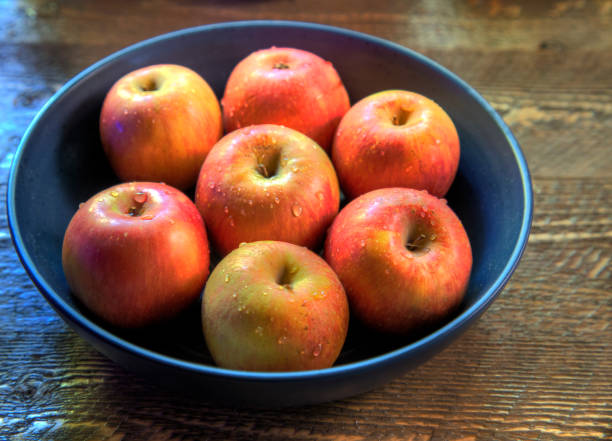 Side view of  Bowl of fugi apples on natural wood surface stock photo