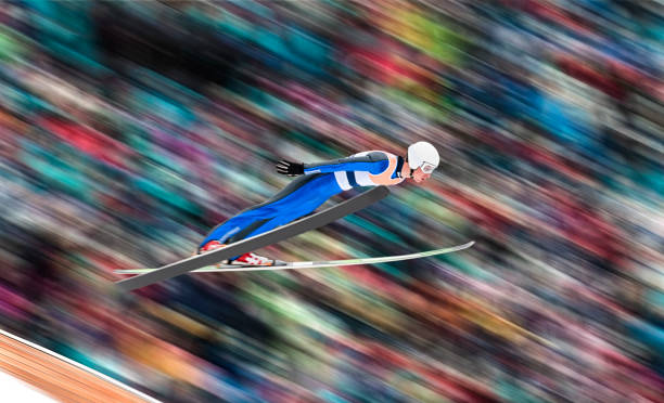Side View of Male Ski Jumper in Mid-air Against Blurred Background stock photo