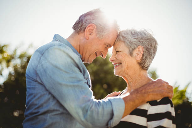 Side view of romantic senior couple looking at each other Side view of romantic senior couple looking at each other in back yard face to face stock pictures, royalty-free photos & images