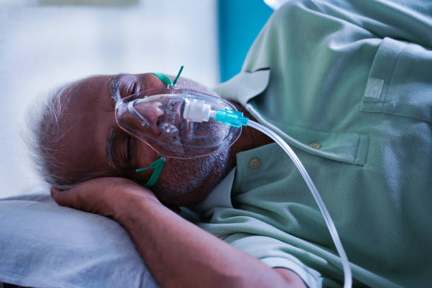 side view of senior ill patient breathing on oxygen ventilator mask due to coronavirus or covid-19 breathlessness viral infection at hospital - luftvägsinfektion bildbanksfoton och bilder