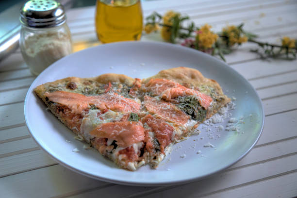 Side view of smoked salmon pizza on white natural wood table stock photo