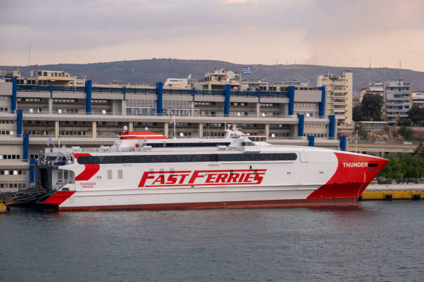 Side view on FAST FERRIES high speed catamaran THUNDER  docking in front of harbor authorities at Piraeus port stock photo