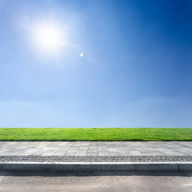 Sidewalk and blue sky above green lawn stock photo