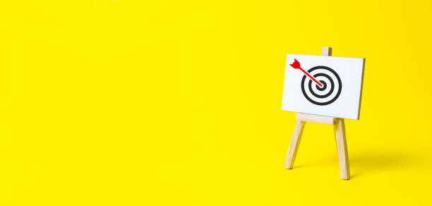 Sign stand with an arrow in the target on a yellow background. Hit exactly on center. Tactics of advertising targeting. advertise campaigns. Goal Achievement and Purposefulness  niche stock pictures, royalty-free photos & images