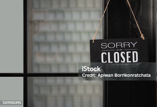 istock Signboard of tell sorry we are closed business and please come back again when situation improved with hanging to door front at shop. 1329105395