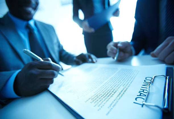 Image of businessman signing contract with two employees near by