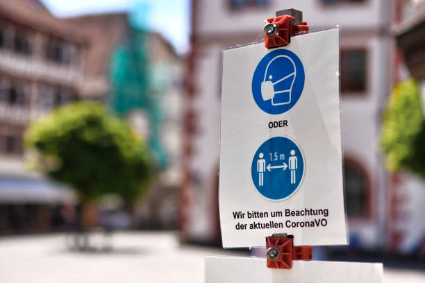 Signs for face mask and distance requirement in German city with text saying "Please pay attention to current Corona regulations" stock photo
