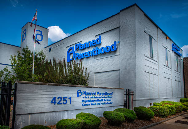 Signs for Planned Parenthood a women's health provider displayed on the side of a facility in Central Westend Saint Louis, MO--Aug 3, 2019 American flag flies next to the last abortion clinic in the state of Missouri with blue and cloudy sky in background. abortion clinic stock pictures, royalty-free photos & images