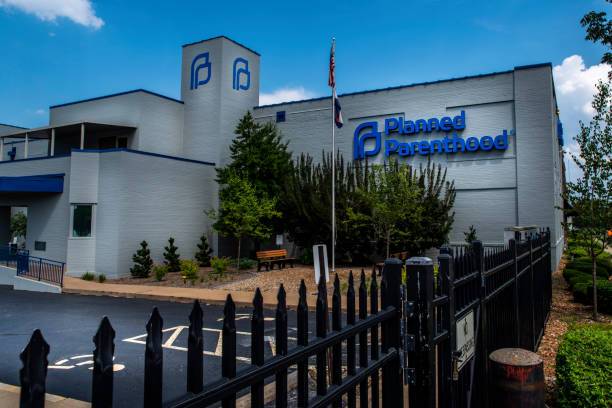 Signs for Planned Parenthood a women's health provider displayed on the side of a facility in Central Westend Saint Louis, MO--Aug 3, 2019 American flag flies next to the last abortion clinic in the state of Missouri with blue and cloudy sky in background. abortion pill stock pictures, royalty-free photos & images