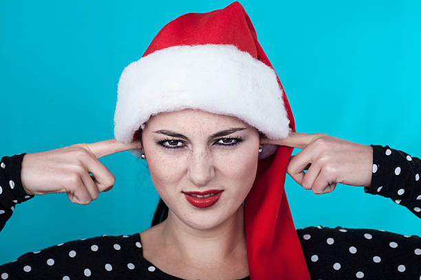 SIlent please portrait of a beautiful young smiling woman with santa hat and fingers in ears Fingers in Ears stock pictures, royalty-free photos & images