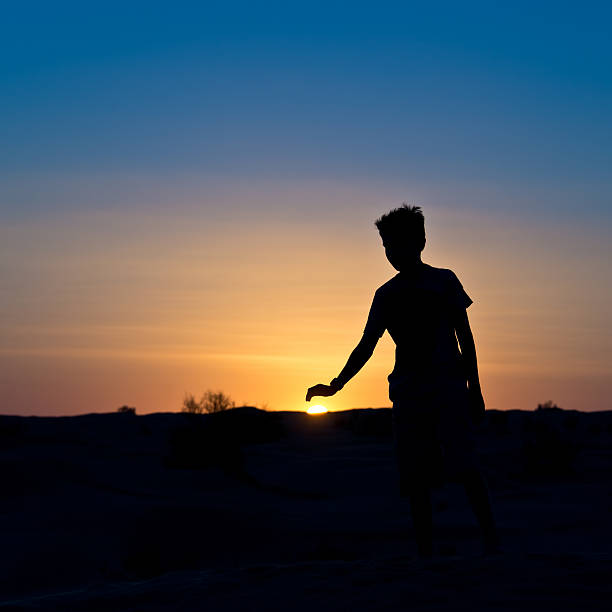 Silhouette of a boy covering the sun with his hand  ghost boy stock pictures, royalty-free photos & images