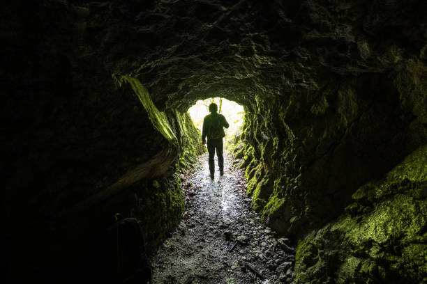 Silhouette of a male person at the cave entrance Man exploring caves in Julian Alps mountains, Slovenia, Europe. old man cave stock pictures, royalty-free photos & images