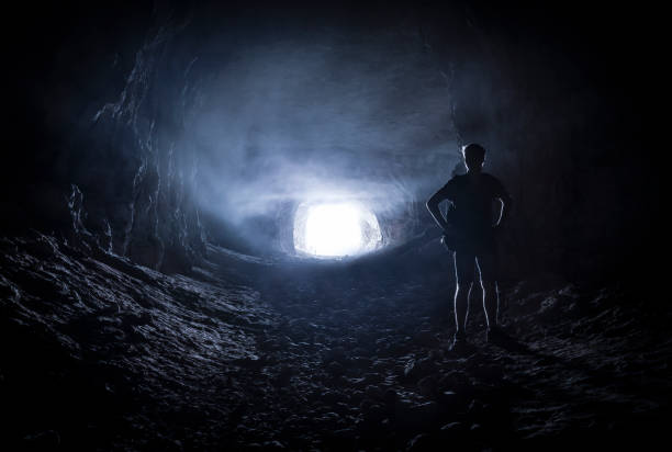 silhouet van een man in een grot - speleologie buitensport stockfoto's en -beelden