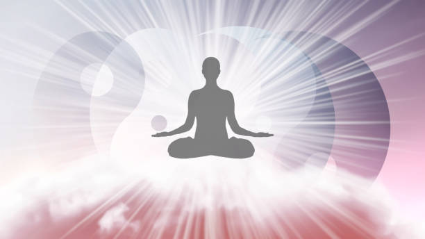 A silhouette of a man in a lotus position with arms spread apart, flying in the sky in a bright white sunlight on the background of the Yin-Yang symbol. Samadhi meditation concept, open mind. stock photo
