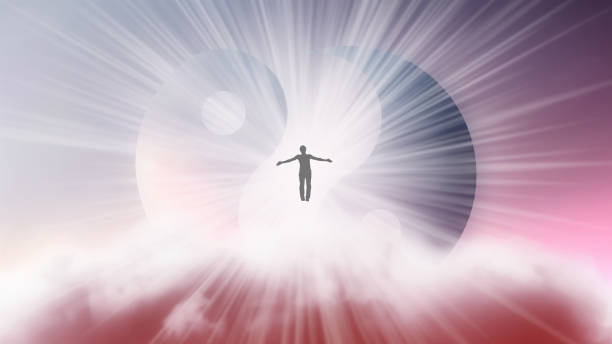 A silhouette of a man with arms spread apart, flying in the sky in a bright white sunlight on the background of the Yin-Yang symbol. Samadhi meditation concept, open mind. stock photo