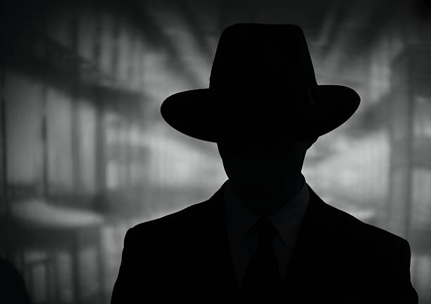 Silhouette of a mysterious man in a hat Silhouette of a mysterious man in a vintage style wide brimmed hat in a close up black and white head and shoulders portrait gangster stock pictures, royalty-free photos & images