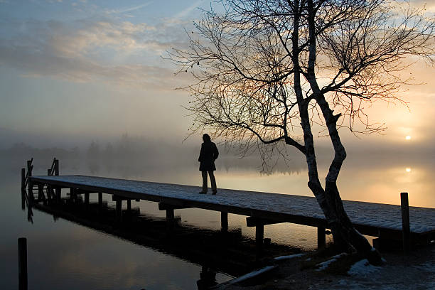 Silhouette of a person alone on a dock stock photo