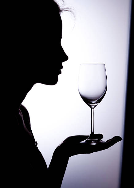 Silhouette of a woman holding a wine glass stock photo