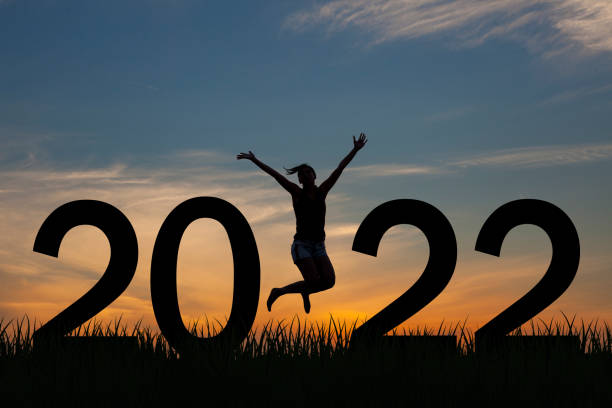 Silhouette of a woman jumping in 2022 on the hill at sunrise stock photo