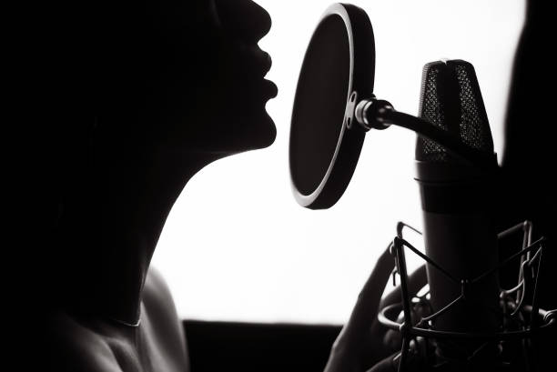 Silhouette of a woman singing a song in a recording studio. stock photo