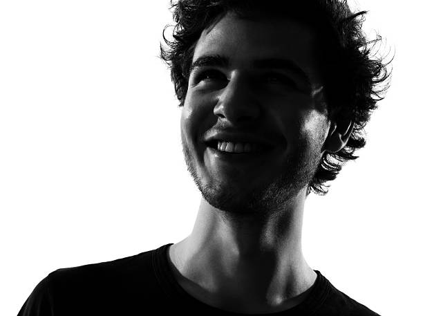 glücklich lächelnd junger mann silhouette - gegenlicht stock-fotos und bilder