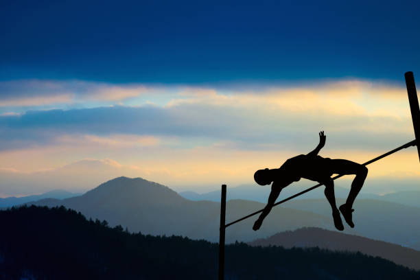 夕暮れ時に棒高跳びの競争の運動選手のシルエット - 棒高跳び ストックフォトと画像