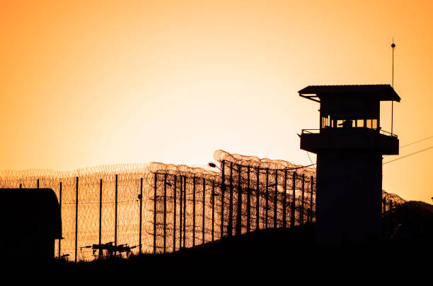 Silhouette of barbed wires and watchtower of prison. stock photo