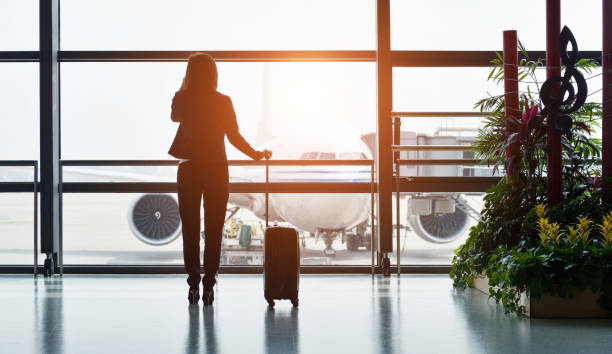 sylwetka podróżnika służbowego dzwoni, czekając na jej lot - business travel zdjęcia i obrazy z banku zdjęć