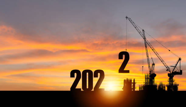 Silhouette of construction site with crane and sunset sky for preparation new year of 2022 stock photo