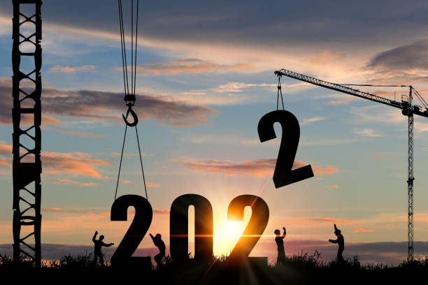 2022년 신년파티를 준비하고 새로운 사업을 바꾸기 위해 크레인과 흐린 하늘을 가진 건설 노동자의 실루엣. - 예측 뉴스 사진 이미지