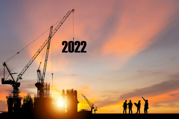 Silhouette of construction worker with crane and sunset sky for preparation new year of 2022 stock photo