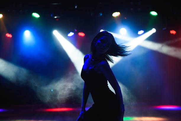 Silhouette of dancing girl against disco lights stock photo