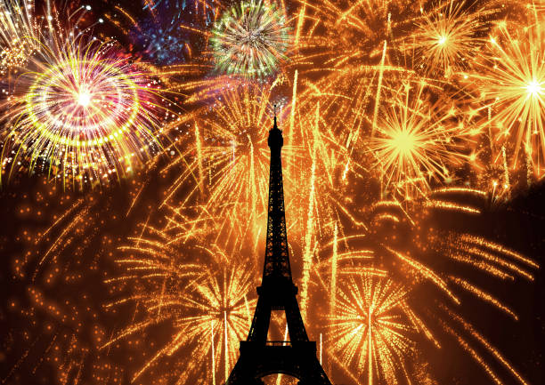 silhouette of eiffel tower illuminated at night by fireworks as holiday celebration stock photo