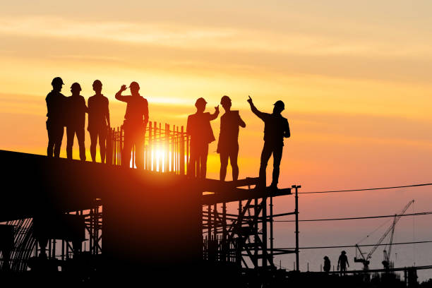 Silhouette of Engineer and worker team on building site, Industrial sector construction site at sunset in evening time stock photo