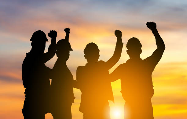 Silhouette of engineer and worker team with clipping path joining hands and celebration with sunset background, Success and Teamwork Concepts stock photo