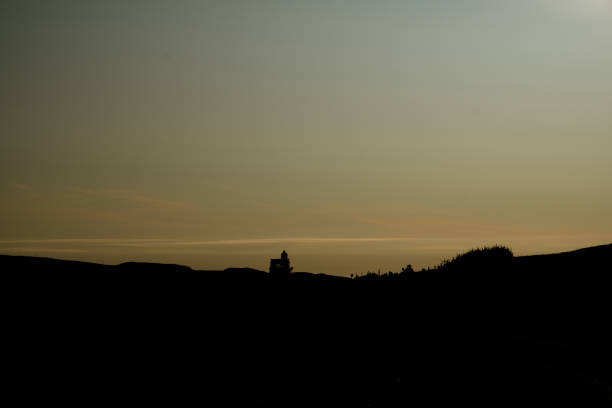 silhouette of figure on top of camper van at sunset stock photo