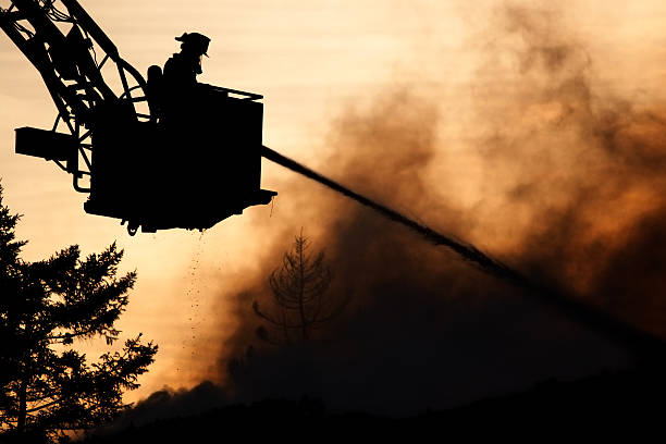 silhouette of firefighter spraying water on fire in bucket stock photo