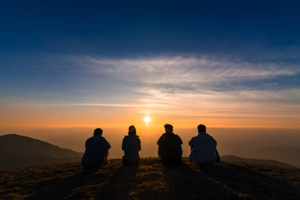 silhouette of friends  sitting together watching sunset for business successful and team work concept. stock photo