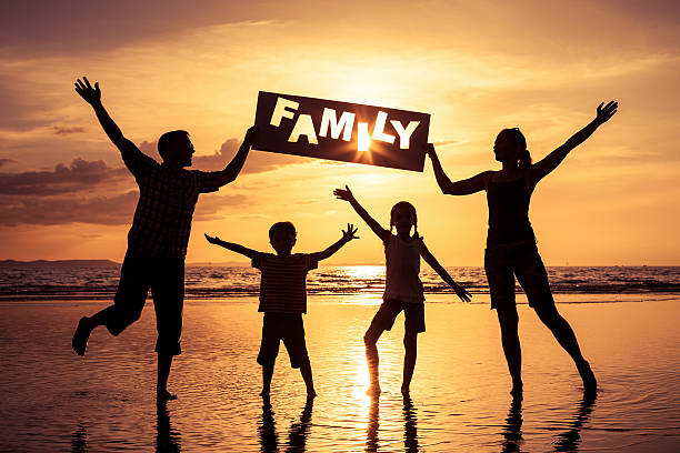 Silhouette of happy family who standing on the beach at the sunset...