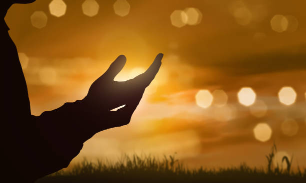 Silhouette of human hand with open palm praying to god stock photo