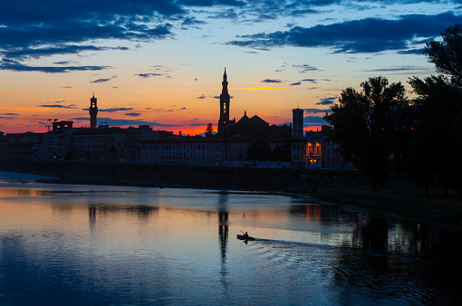 A silhouette of kayaker navigates on the Arno River in the heart of Florence, Italy at sunset.