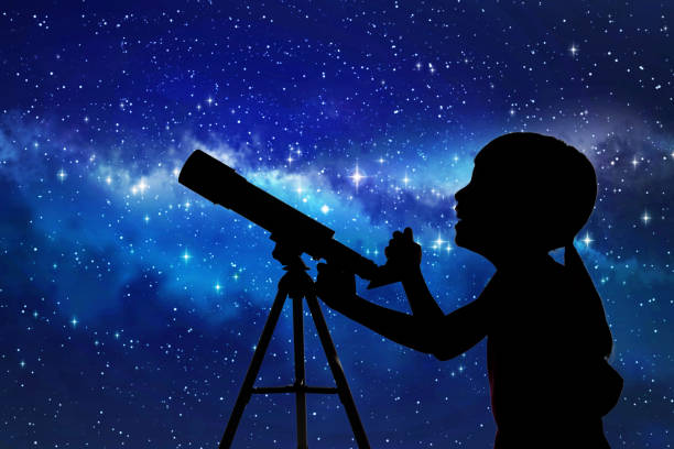 Silhouette of little girl looking through a telescope stock photo