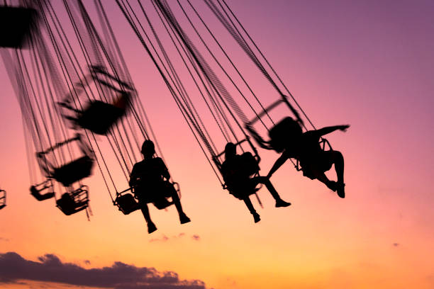 silhouette of people having fun in mechanical game, flying chairs in Guatemala, Retalhulehu. Tropical afternoon. silhouette of people having fun in mechanical game, flying chairs in Guatemala, Retalhulehu. amusement park ride stock pictures, royalty-free photos & images