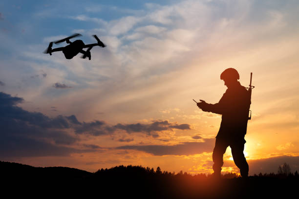 Silhouette of soldier are using drone and laptop computer for scouting during military operation. stock photo