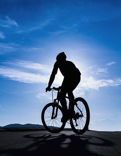 Silhouette of the cyclist riding stock photo